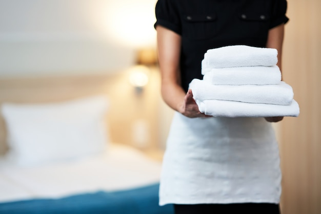 maid with fresh towels in hotel room