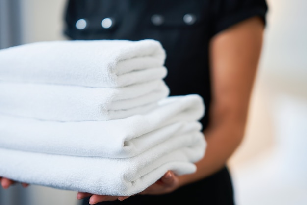 maid with fresh towels in hotel room