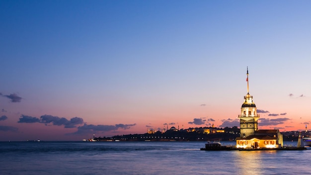 Maiden Tower or Kiz Kulesi with floating tourist boats on Bosphorus in Istanbul at night