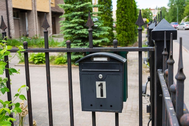 Mailbox of a private house a black metal mailbox installed on the fence grid of a house