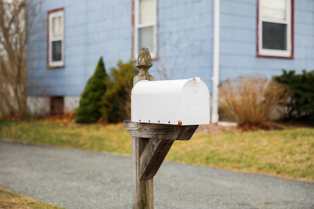 Photo a mailbox sits on a post in front of a blue house.