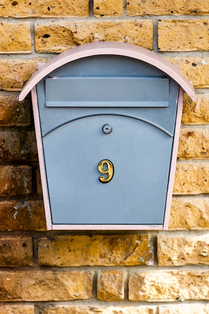 Почтовый ящик с номером девять на каменной стене из желтого кирпича. Фото высокого качества