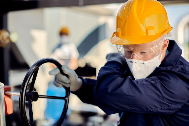 Ingegnere di manutenzione con maschera facciale che tossisce nel gomito al lavoro