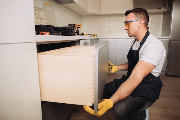 Человек обслуживания устанавливая кухонную мебель