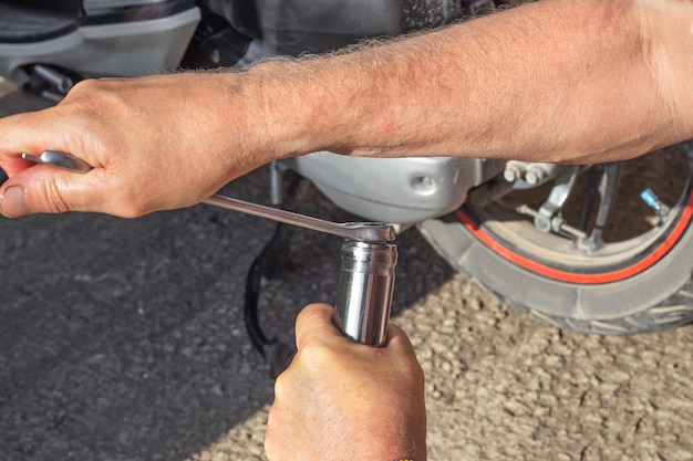 Foto manutenzione e riparazione di motocicli un meccanico di auto utilizza una chiave per serrare la spina sul