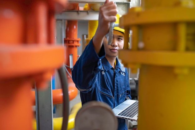 Photo maintenance technician at a heating plantpetrochemical workers supervise the operation of gas and oil pipelines in the factoryengineers put hearing protector at room with many pipes