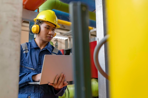 Photo maintenance technician at a heating plantpetrochemical workers supervise the operation of gas and oil pipelines in the factoryengineers put hearing protector at room with many pipes