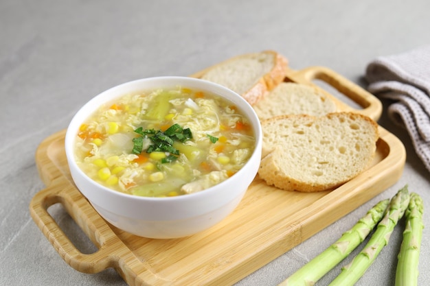 Maïs en asperges met eierdruppelsoep in witte kom en krokant brood