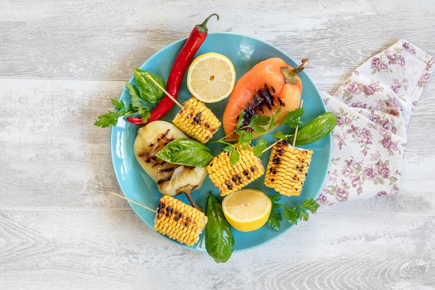 Maïs gebakken in olijfolie met peper, zout en basilicum op een blauwe schaal op een lichte ondergrond Vegetarisch veganistisch menu