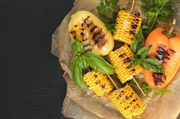 Maïs gebakken in olijfolie met peper, zout en basilicum op een blauwe schaal op een zwarte stenen ondergrond Vegetarisch veganistisch menu