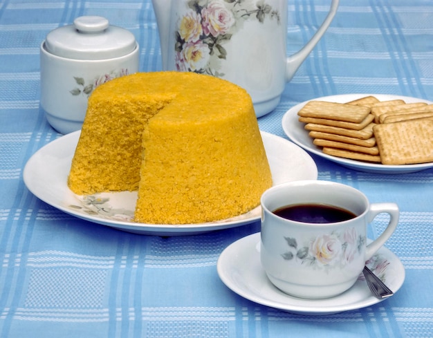 Maiscouscous aan tafel met een kopje koffie en gekookte maiskolven Braziliaans eten