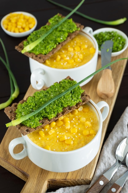 Foto maïssoep met verse knoflookpastei in witte kom gezond voedsel op zwarte houten achtergrond veganistische keuken