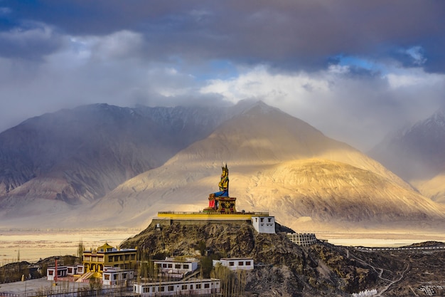 The Maitreya Buddha statue with Himalaya mountains in the background from Diskit Monastery, India.