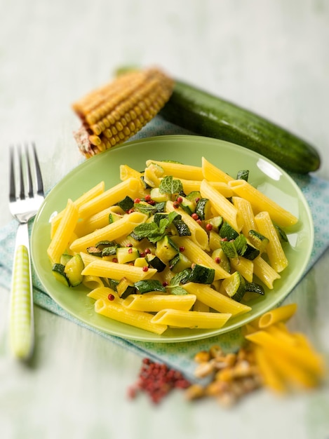 Foto pasta di mais con zucchine e pepe rosa a fuoco selettivo