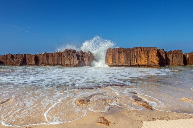 A majestic beach with towering cliffs motionless blue water and a clear sky