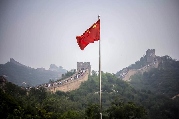 Photo the majestic great wall of china near beijing on a summer day with the chinese flag flying