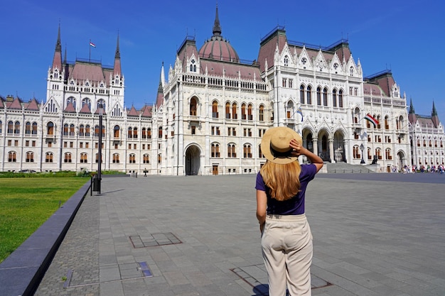 Maestoso palazzo del parlamento ungherese a budapest ungheria giovane donna turistica alla scoperta dei monumenti di bellezza dell'europa