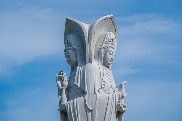 Фото Величественная белая статуя будды на фоне голубого неба леди будда бодхисаттва милосердия в пагоде буу лам ту, которая привлекает туристов для духовного посещения по выходным в вунгтау, вьетнам