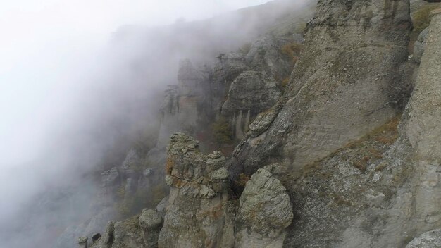 Majestical mountains in clouds with yellow autumn trees shot landscape with beautiful high rocks and