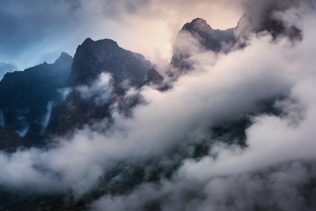 Majestical scene with mountains in clouds in overcast evening