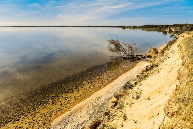 Majestueus zeegezicht met een zandige kustlijn onder een blauwe bewolkte hemel