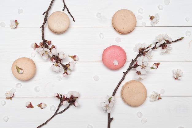 Makaronkoekjes en bloemen op witte houten achtergrond