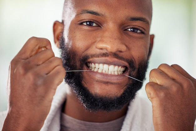 치실을 일상 생활의 일부로 만드십시오. 집에서 치실을 하는 젊은 남자의 샷