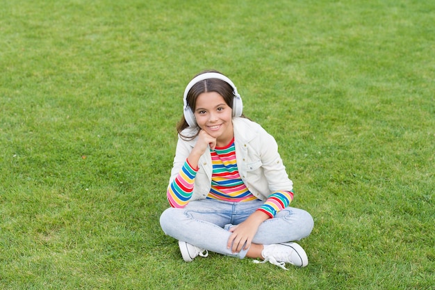 Make it happen luister naar muziek terwijl je buiten ontspant kind meisje geniet van muziek groen gras weide prettige tijd kind koptelefoon luister muziek cool meisje koptelefoon luistert muziek educatieve podcast