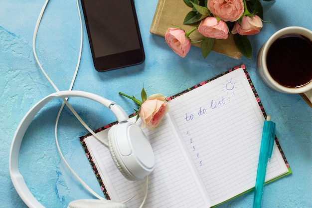 Crea l'elenco concettuale cuffie per smartphone tazza da caffè e notebook vista dall'alto piatta