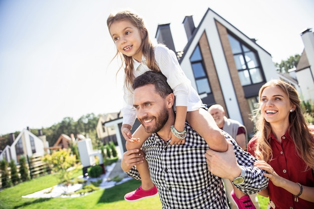 Make me happy. Pleased bearded man keeping smile on his face while playing with his kid