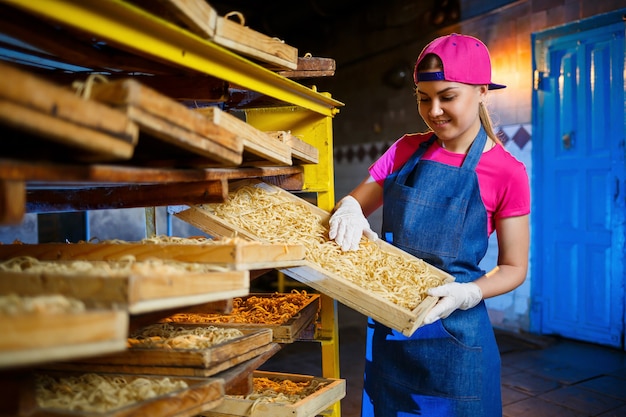 Make the noodles. Pasta factory. Spaghetti production. Raw pasta. Worker with a box of pasta. Girl works in the production of pasta