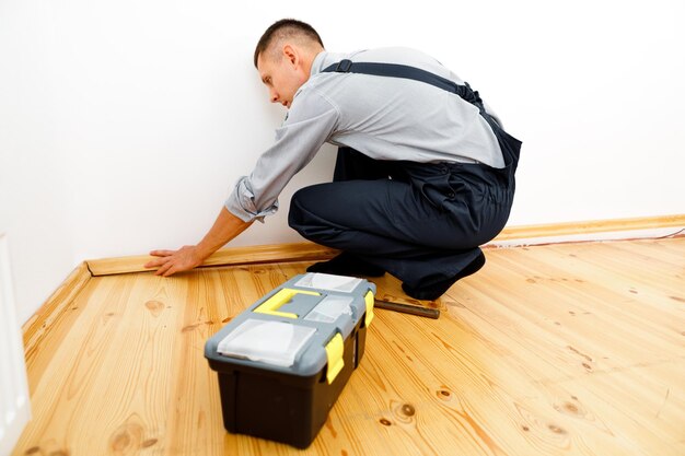 To make repairs. installing a new skirting board. a man makes\
repairs in a room