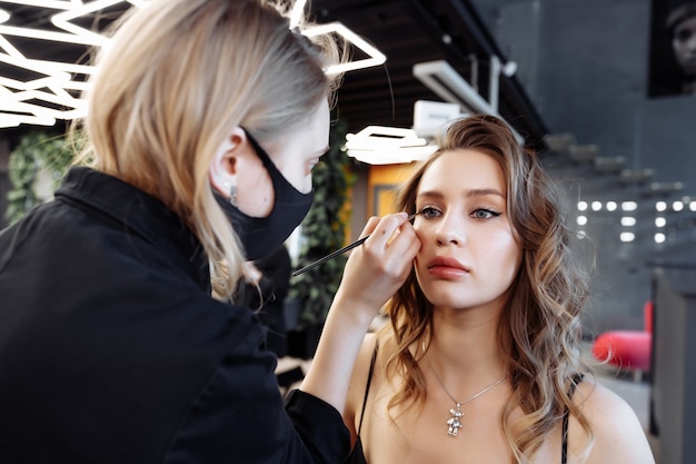 Make-up aanbrengen op de wenkbrauwen in een schoonheidssalon foto van hoge kwaliteit