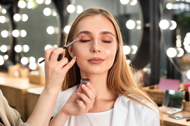 Make-up artist applying eyeshadow on woman