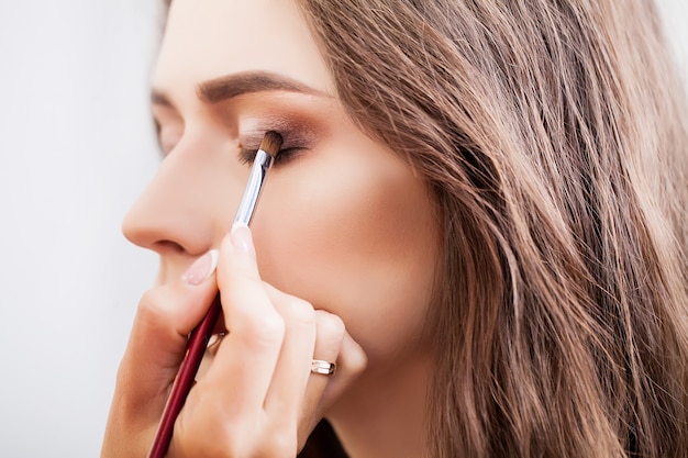 Make-up artist doing make-up girl in the salon, beauty concept