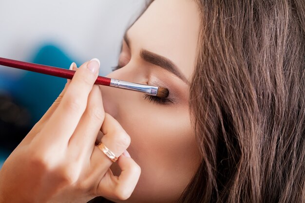 Make-up artist doing make-up girl in the salon, beauty concept