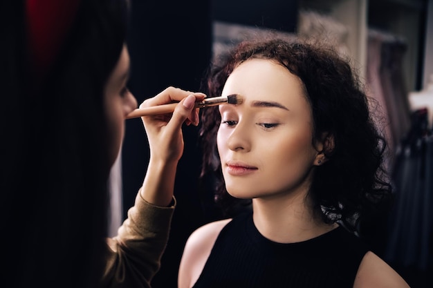 Make up artist doing maquillage to woman