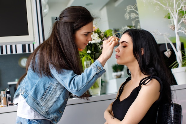 Truccatore che fa trucco professionale di una giovane modella