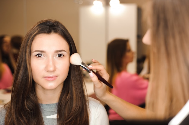 Truccatore che fa trucco professionale di giovane donna.