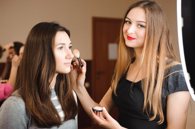 Make up artist doing professional make up of young woman.