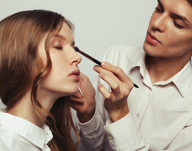 Make up artist doing professional make up of young woman