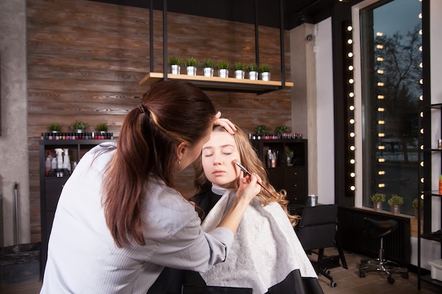 Make up artist doing professional make up of young woman