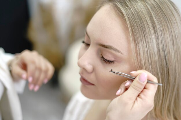 Foto make-up artist in de studio steekt valse wimpers op jonge mooie model