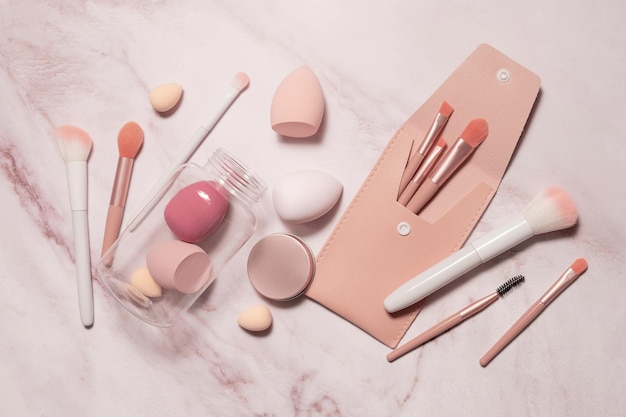Make-up artist's tools in roze op een marmeren kaptafel: borstels voor poeder, blush, wenkbrauwen, schaduwen en sponzen voor concealer en foundation.