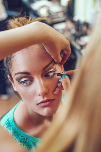 Make-up artist who is applying makeup on beautiful young caucasian woman.