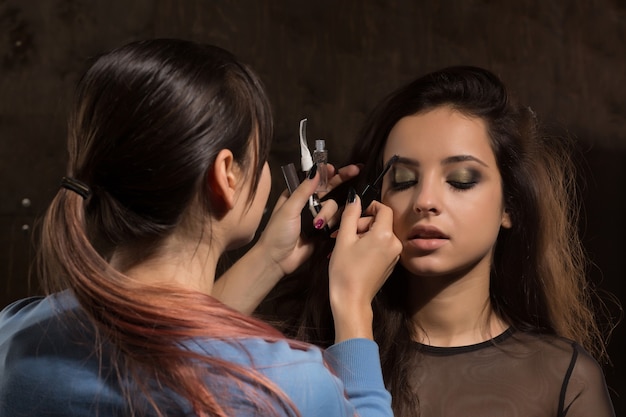 Make up artist works with young model at the studio