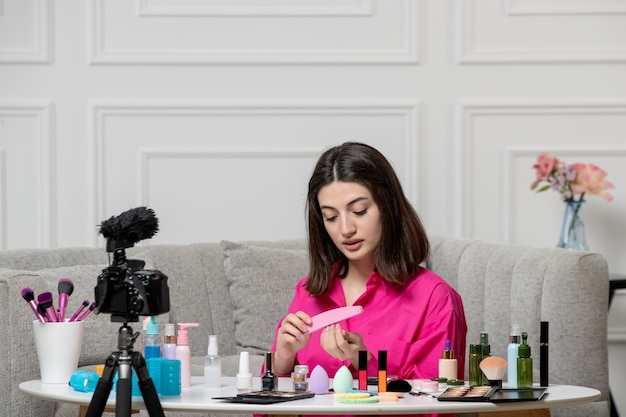 Make up blogger cute lovely beautiful young lady recording video on camera filing nails