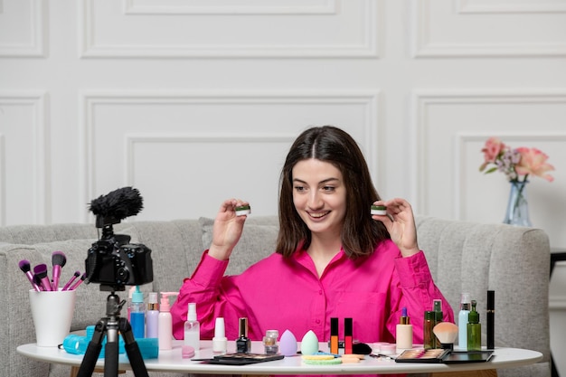 Make up blogger cute lovely beautiful young woman recording video on camera with two creams