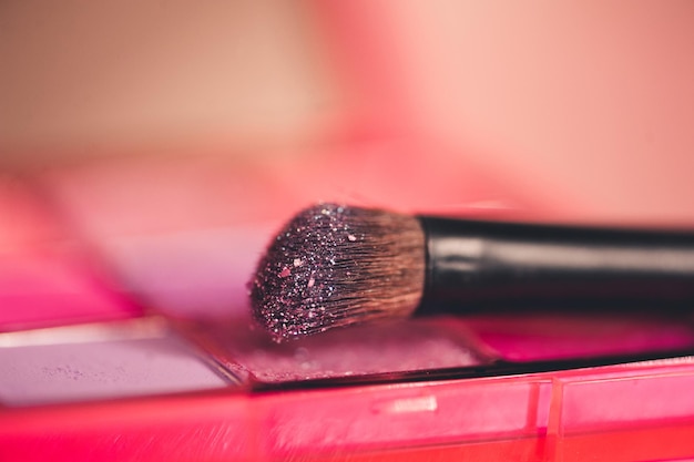 Make up brush with glitter shaows closeup. Selective focus.