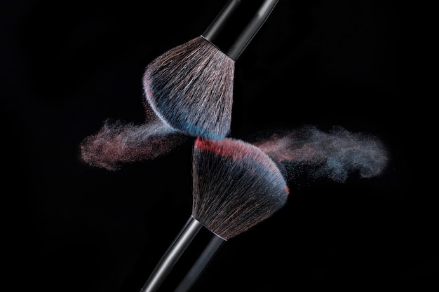 Make up brush with powder splashes on black background